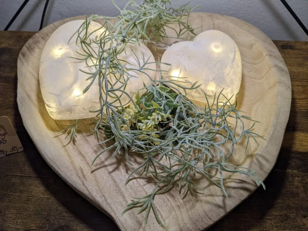 Leuchtende Kugelobjekte auf einem herzförmigen Holzteller