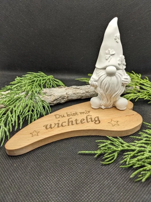 Kleine Wichtelfigur auf einem beschrifteten Holzschild